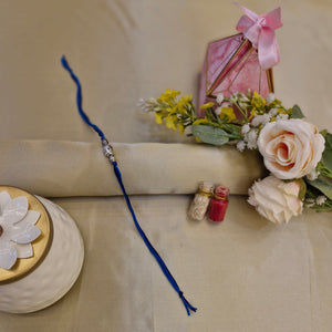Rakhi with flowers and a decorative box on a beige background