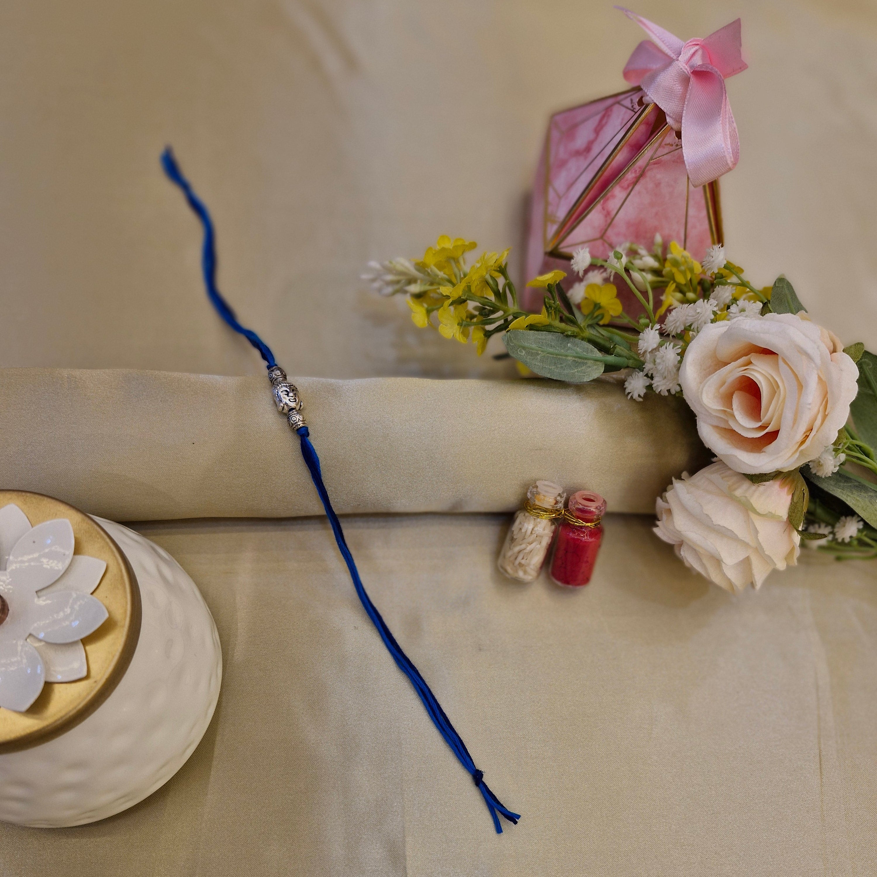 Rakhi with flowers and a decorative box on a beige background