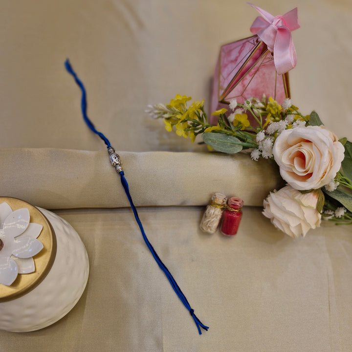 Rakhi with flowers and a decorative box on a beige background