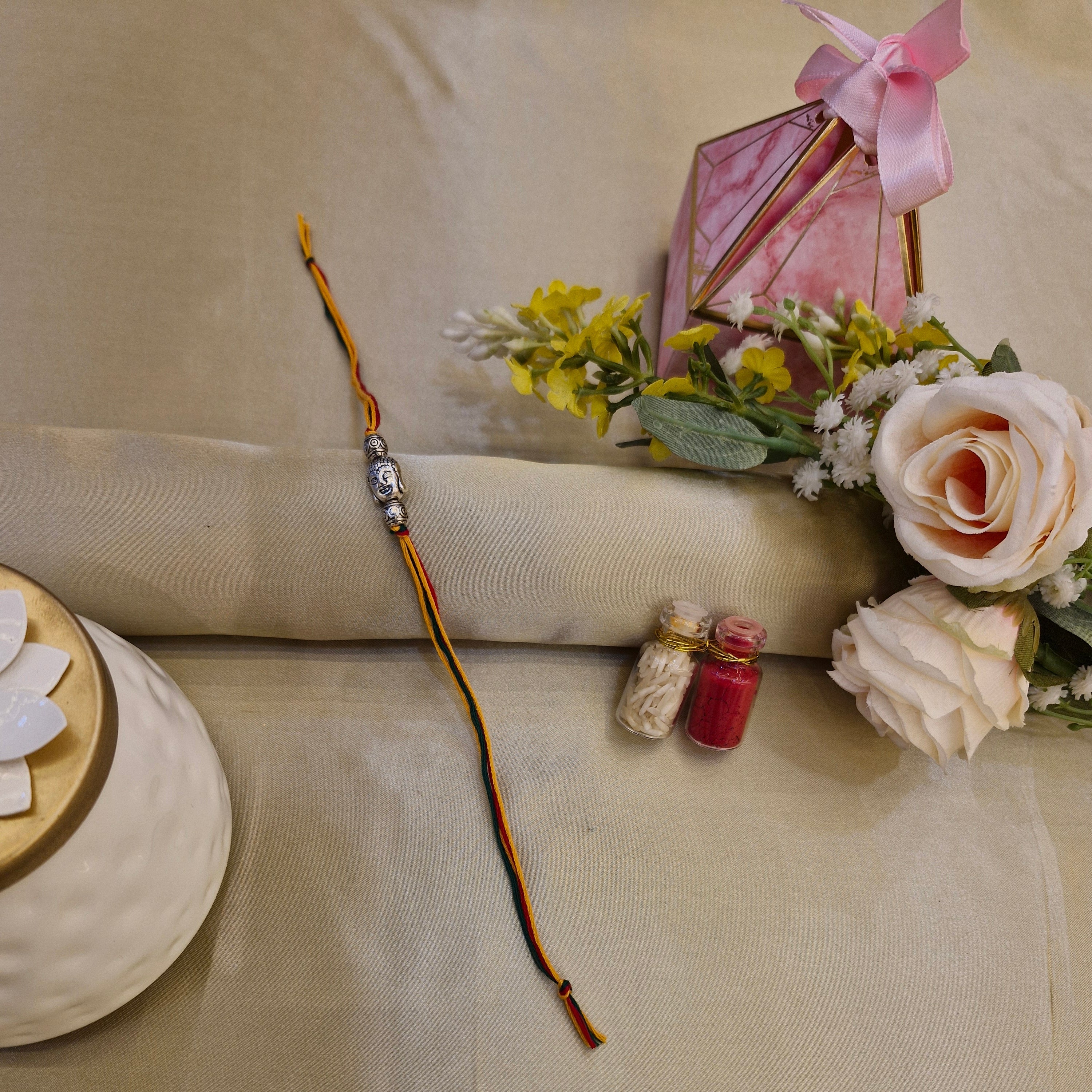 Decorative arrangement with flowers, a small lantern, and a hairpin on a beige surface.